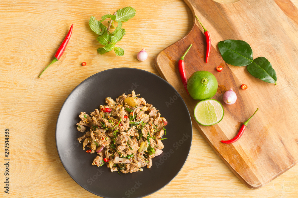 Spicy Minced Duck Salad In a black plate on a wooden table Spicy Minced Duck Salad In a black plate on a wooden table