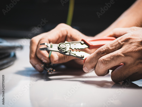 Closeup at the hand of an electrician is using electrical stripping pliers in industrial applications.