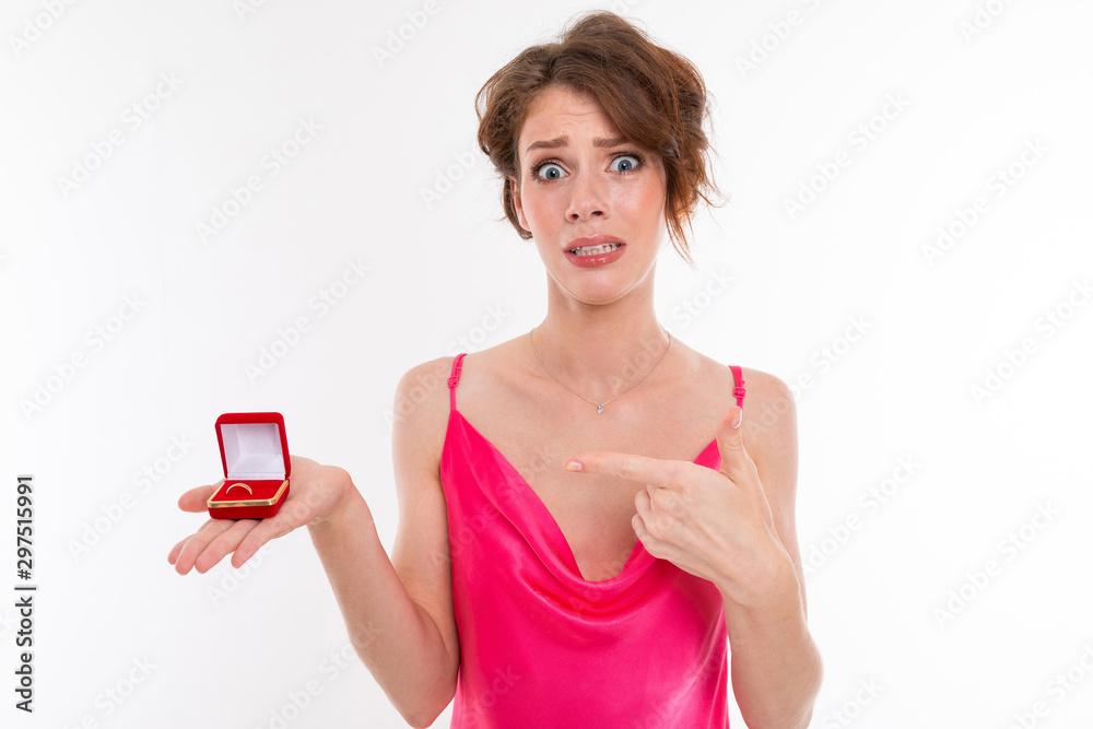 Young beautiful girl with wavy brown patched hair, clean skin, flat teeth, beautiful smile, in pink jersey, holding a training ring box and not very happy with the offer Young beautiful girl with wavy brown patched hair, clean skin, flat teeth, beautiful smile, in pink jersey, holding a training ring box and not very happy with the offer
