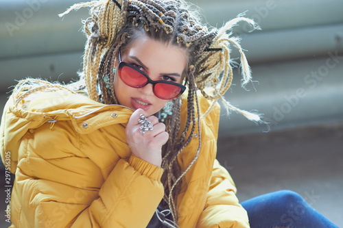 portrait of an eccentric modern young woman, bright make-up sunglasses, and a crazy hairstyle. cocky teen millennial
