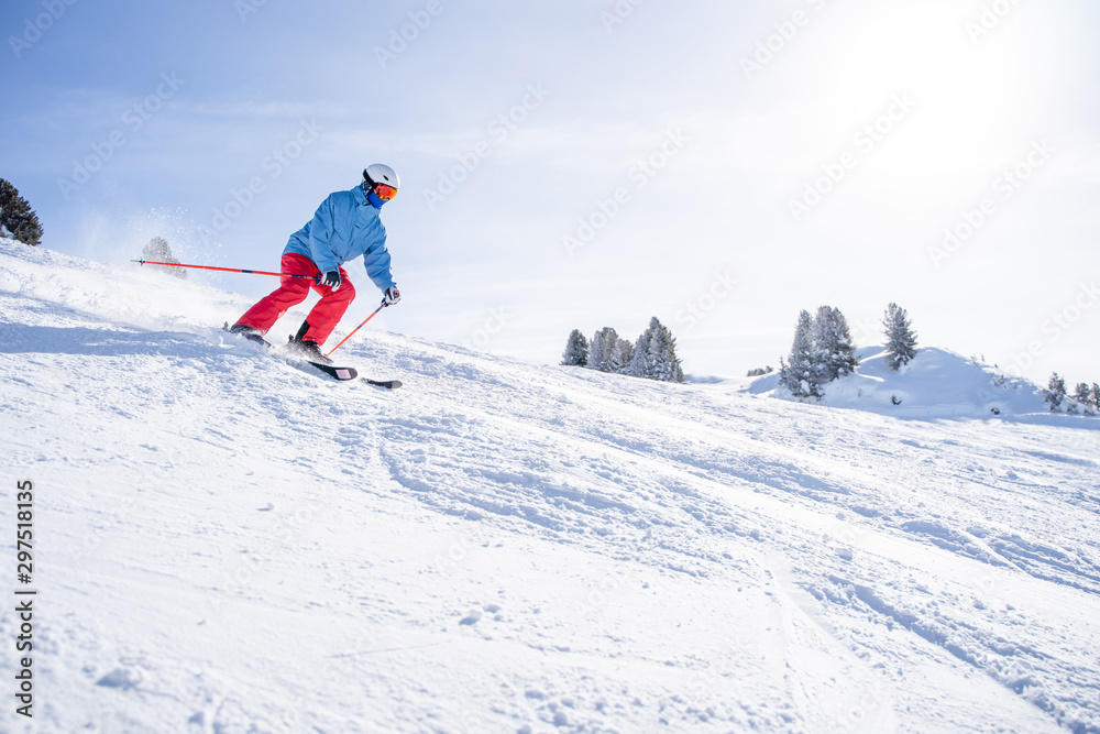 Athletic man in helmet and mask skiing on snowy slope .
