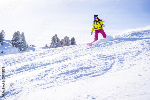 Photo of young athlete woman in helmet snowboarding at winter resort.