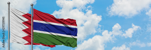 Bahrain and Gambia flag waving in the wind against white cloudy blue sky together. Diplomacy concept, international relations.