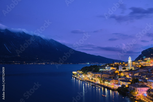 Panoramic view of night city Limone Sul Garda region Trento Lake Garda Italy. A popular resort town. Summer time of the year. Aerial view. City night lanterns, reflection of lamps.