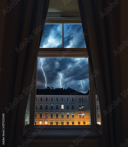 Window view of sparkling lightning in the old town. Concept on the theme of weather, natural disasters, apocalypse, etc. photo