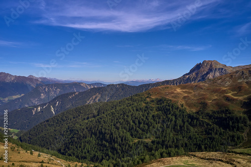 Aerial view of the Alps surrounded by meadows, forests and mountains. Flying on drone.