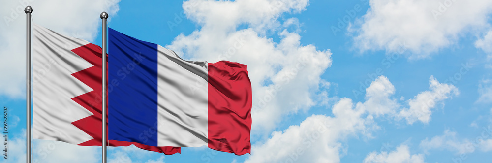 Bahrain and Reunion flag waving in the wind against white cloudy blue sky together. Diplomacy concept, international relations. Bahrain and Reunion flag waving in the wind against white cloudy blue sky together. Diplomacy concept, international relations.