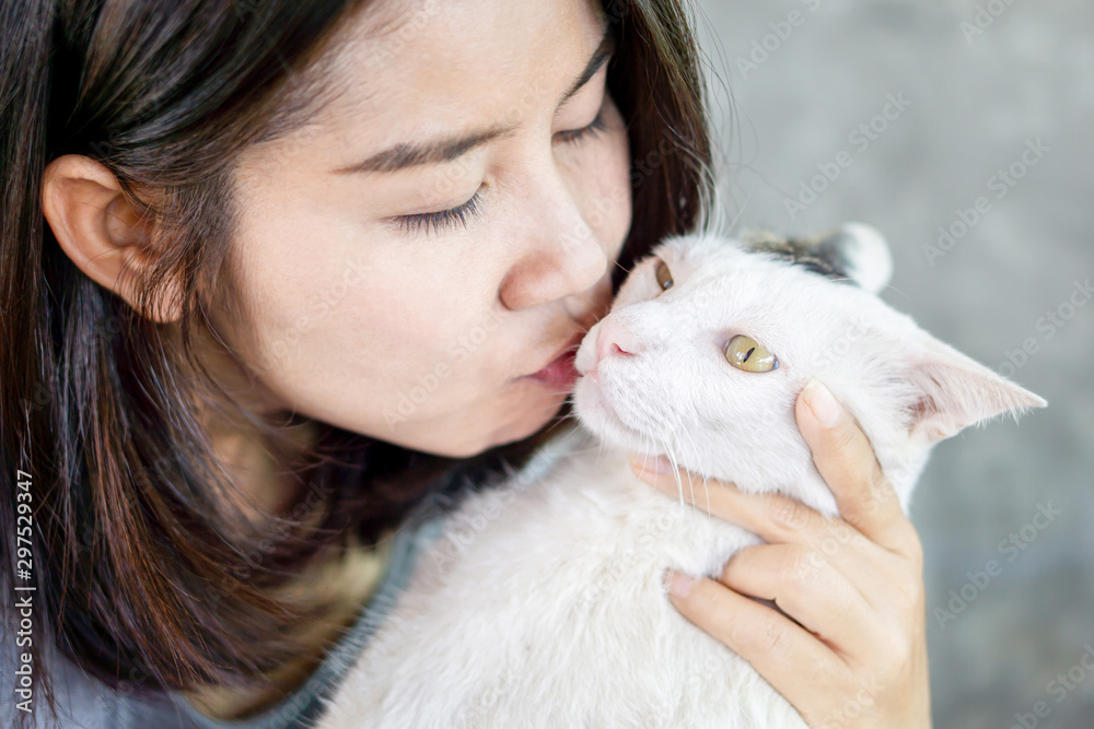 Asian woman kissing cute white cat closeup Asian woman kissing cute white cat closeup