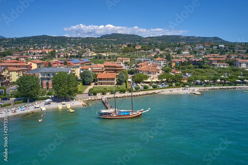 Aerial photography. Beautiful coastline. In the city of Bardolino, Lake Garda is the north of Italy. View by Drone. Large sailboat parked in port.