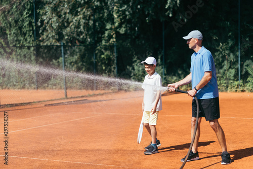 Tennis Coach Spraying a Clay Court with Water © Microgen