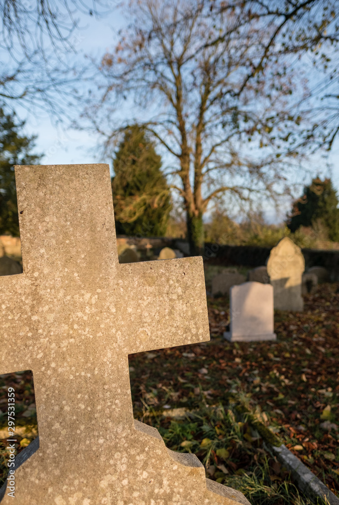 Shallow focus of an old gravestone lit by golden evening light during late autumn.