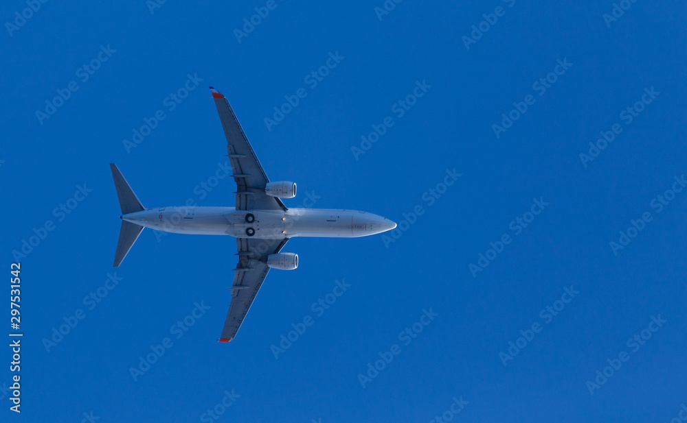 medium size blue passenger airplane on clear sky background. bottom view a few seconds before landing. composition photography. flying overhead to destination airport. travel and journey concept.