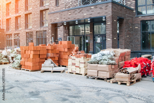 building materials, pallets of bricks and fire hoses are stacked in pile on street in front of apartment complex