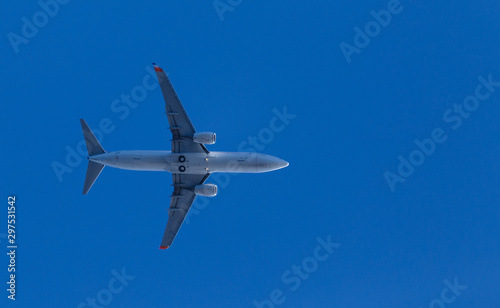 medium size blue passenger airplane on clear sky background. bottom view a few seconds before landing. composition photography. flying overhead to destination airport. travel and journey concept.