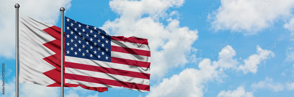 Fototapeta premium Bahrain and United States flag waving in the wind against white cloudy blue sky together. Diplomacy concept, international relations.