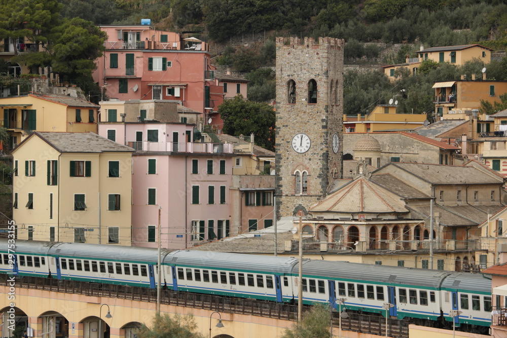 Train passes inside the village of Monterosso al Mare. In the background the church with the bell tower.