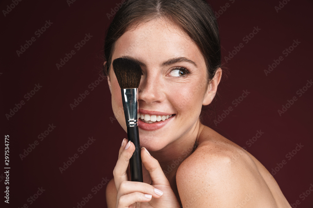 Image of joyful half-naked woman using makeup brush Image of joyful half-naked woman using makeup brush