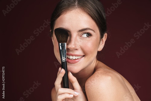 Image of joyful half-naked woman using makeup brush