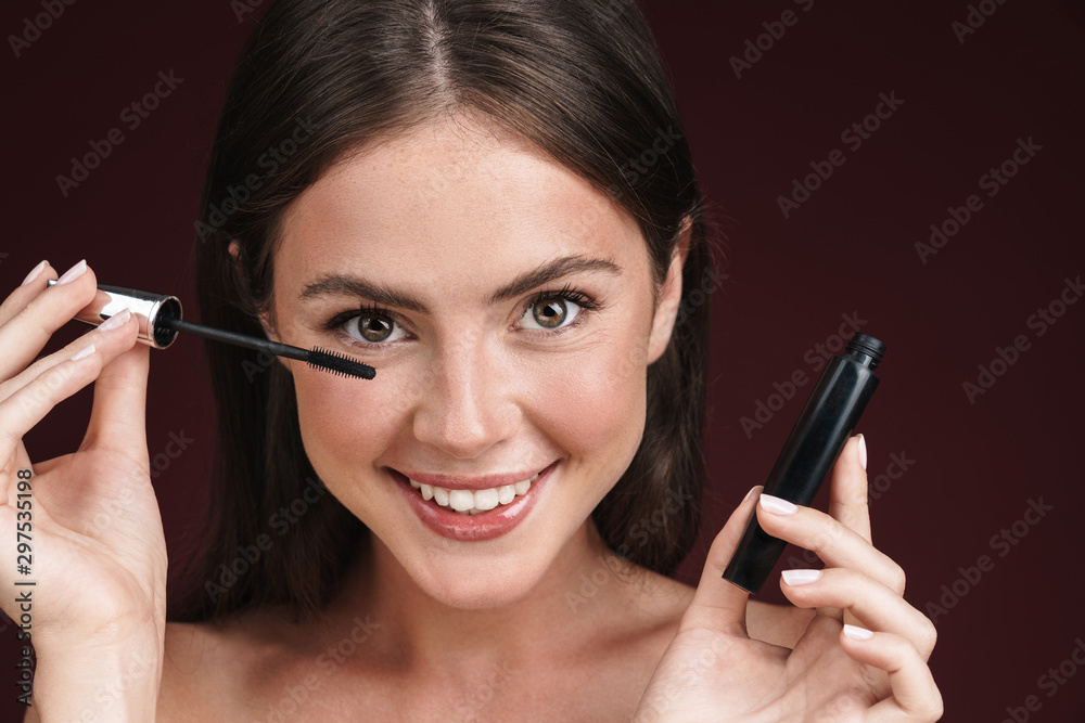 Image of smiling half-naked woman looking at camera and using mascara Image of smiling half-naked woman looking at camera and using mascara