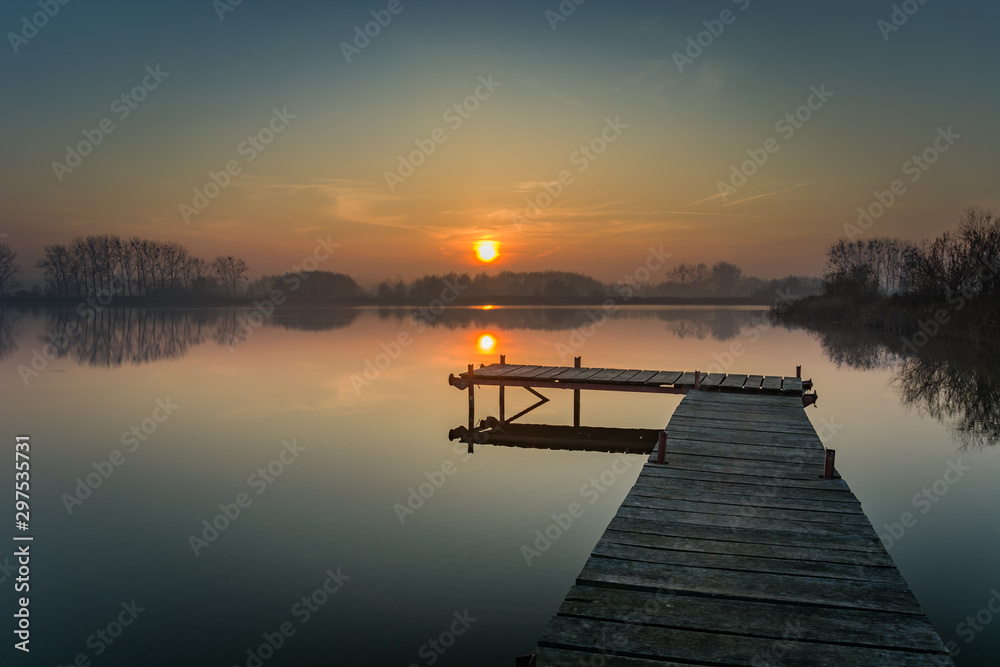 Obraz premium Wooden jetty on a calm lake, evening sky and sunset