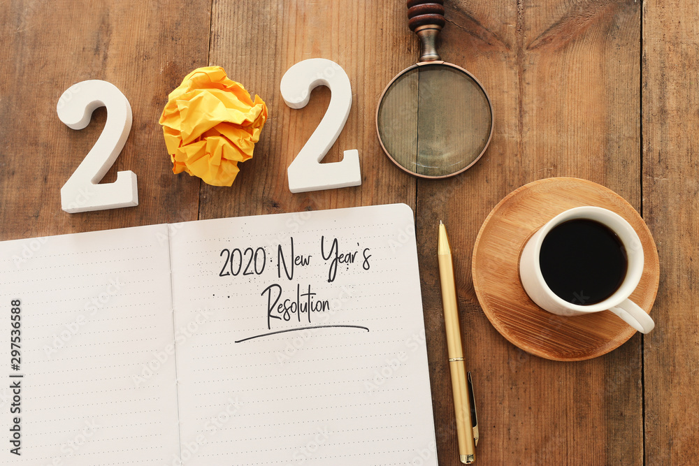 Plakat Business concept of top view 2020 year's resolution list with notebook, cup of coffee over wooden desk