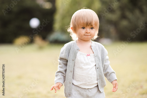 Funny baby girl 1-2 year old walking outdoors over nature background. Summer season. Childhood.