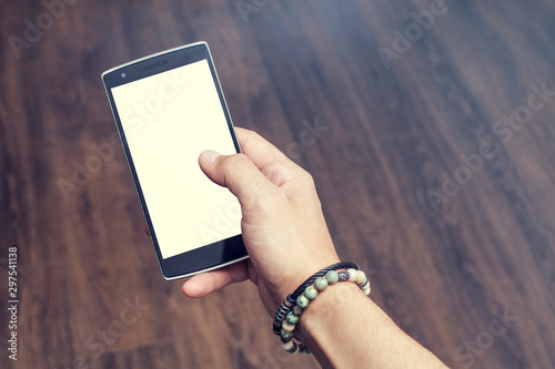 closeup of smart phone held by male hand with bracelet. White screen for app or website placement