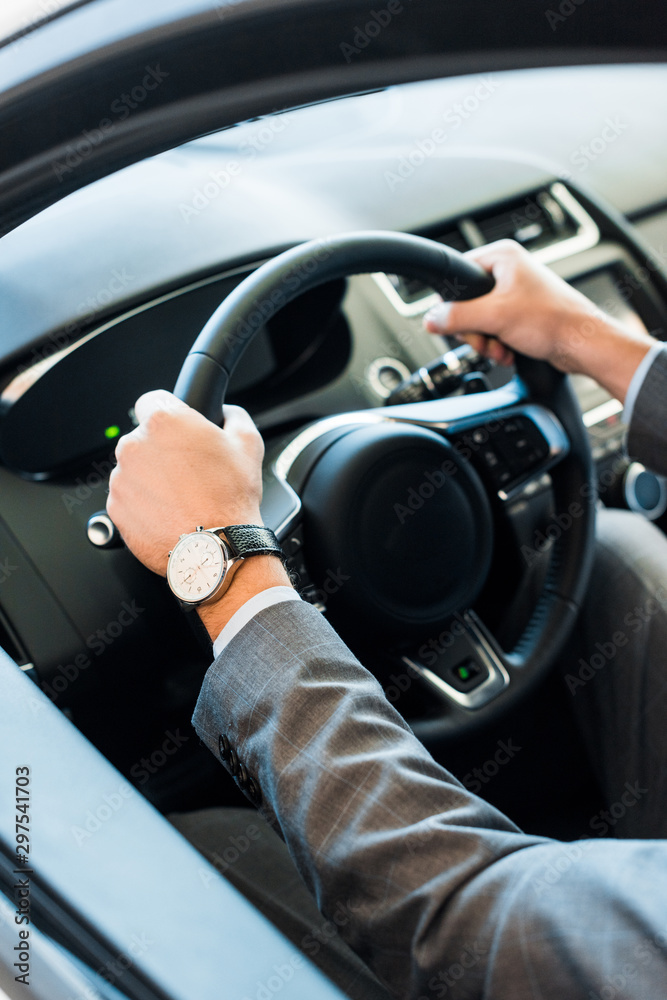 cropped view of man holding steering wheel while sitting in car