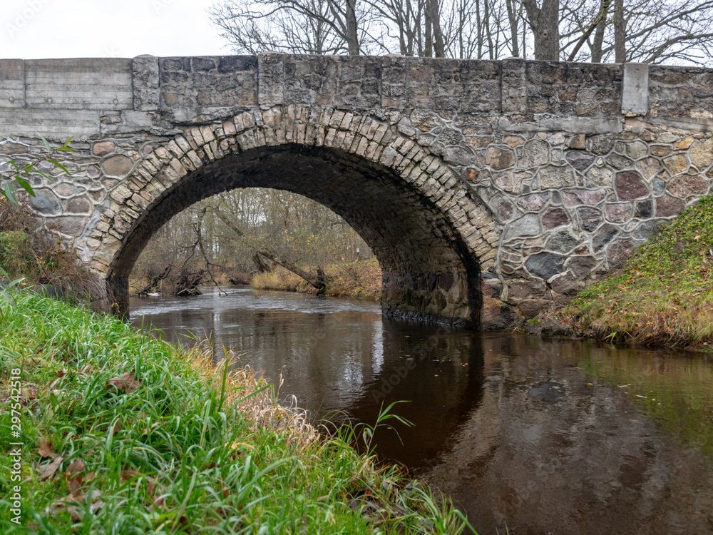 beautiful stone arched bridge over the small river, autumn day
