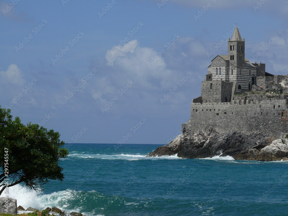 Church of San PIetro in Portovenere, built on a rock overlooking the sea. Sky with clouds and blue sea waves.