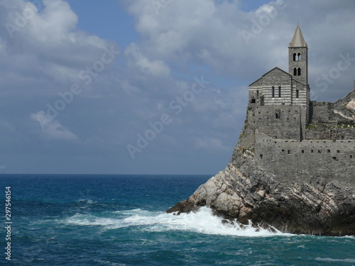 Church of San PIetro in Portovenere, built on a rock overlooking the sea. Sky with clouds and blue sea waves.