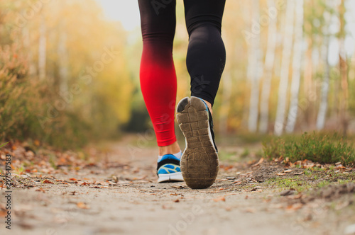 Athletic man running in nature Trail runner working out in the forest. Legs close up with shoe sole . Healthy body exercise sport concept. Bright colorful photo