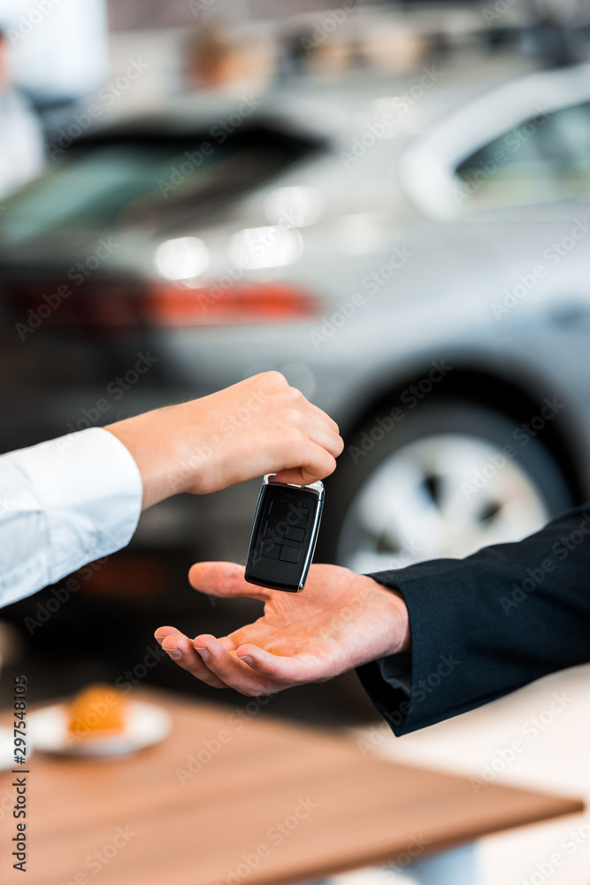 cropped view of woman giving car key to man