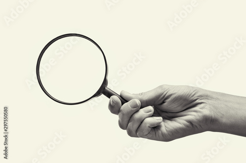 Female hand holding the magnifying glass on isolated background. Black and white image.