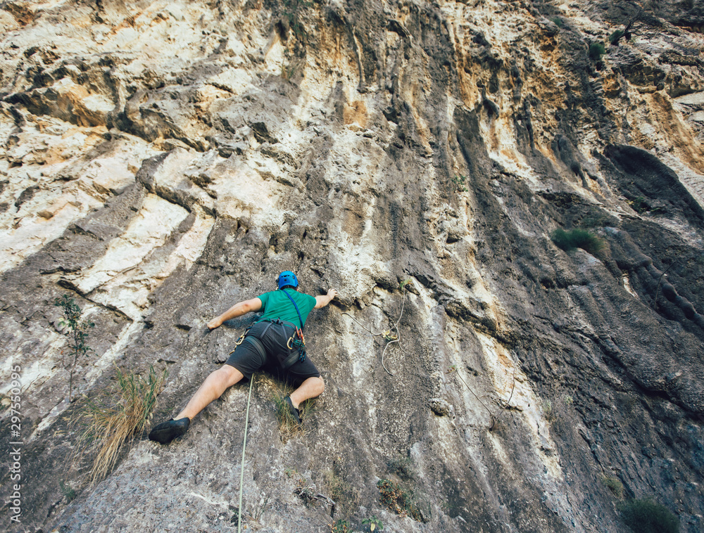 Man with a rope engaged in the sports of rock climbing on the rock.