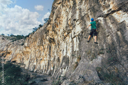 Man with a rope engaged in the sports of rock climbing on the rock.