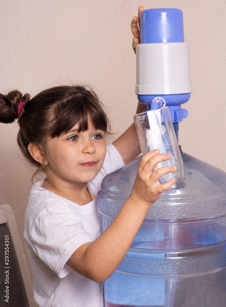 Child girl is drinking water from manual drinking water pump at home