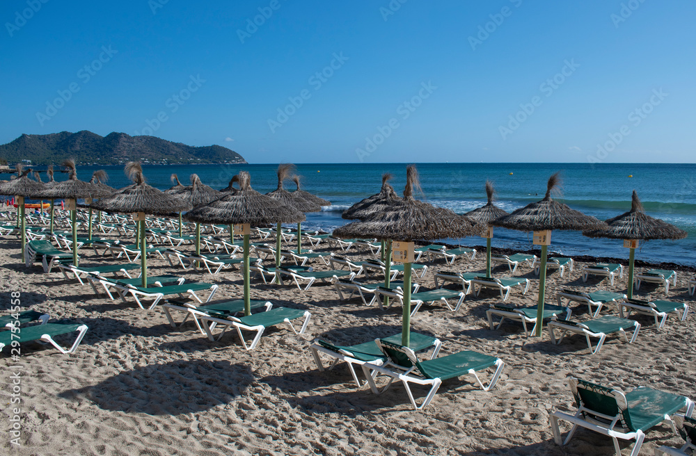 Cala Millor Beach early morning with empty sunbeds and umbrellas awaiting the holidaymakers. Cala Millor Beach early morning with empty sunbeds and umbrellas awaiting the holidaymakers.