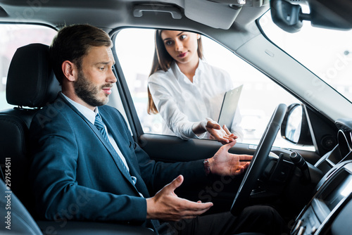 attractive woman looking at handsome bearded man gesturing while sitting in car