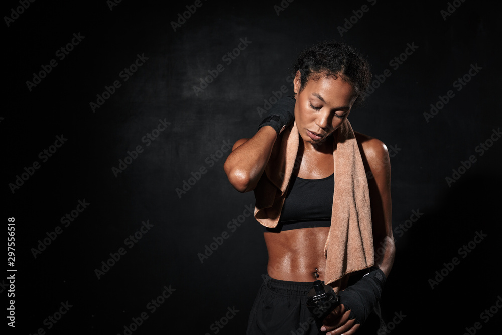 Image of african american woman in boxing hand wraps holding water bottle