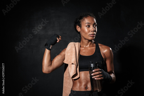 Image of healthy african american woman in boxing hand wraps showing her bicep © Drobot Dean