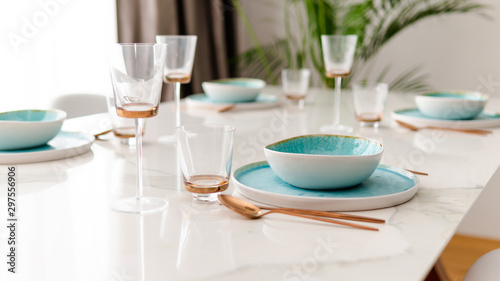 Close-up of served table in a luxury restaurant at the holiday eve. Serving dishes  glass wine glasses and gold cutlery.