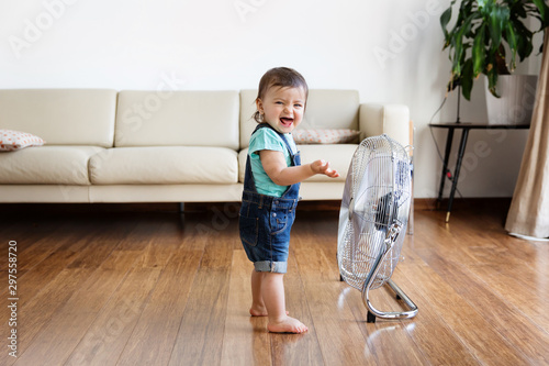 Laughing toddler girl standing in front of fan photo