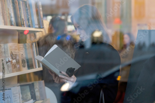 Tableau sur toile Beautiful girl reading a book in a bookstore