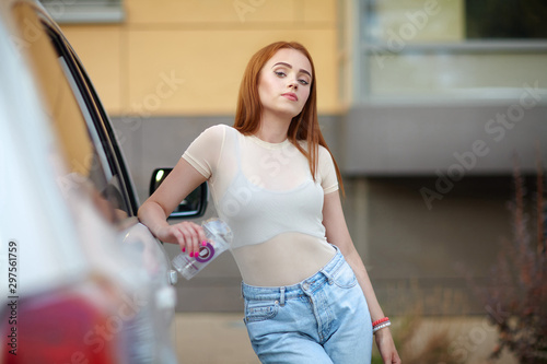Young girl with red hair stands and smiles on a city street