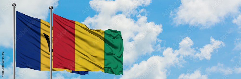 Obraz premium Barbados and Guinea flag waving in the wind against white cloudy blue sky together. Diplomacy concept, international relations.