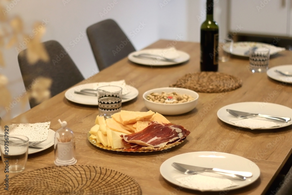 Table set for dinner party with plates, bread, prosciutto and cheese. Selective focus.