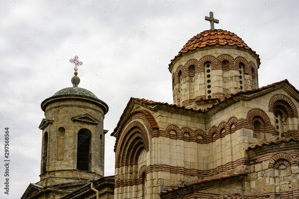 Fototapeta premium Church St. John Baptist, built in 8th century against cloudy sky. Closeup temple building built and Crimean stone. On bell tower and domes church Orthodox crosses.