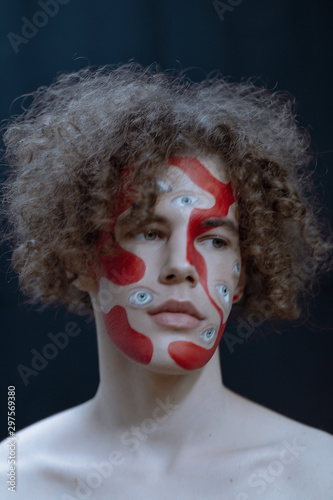 Man studio portrait with makeup for halloween. Abstraction on the face and many eyes.