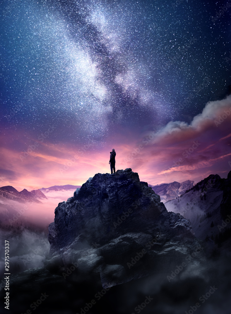 Fototapeta premium Nocne niebo z długim czasem ekspozycji. Mężczyzna stojący na wysokiej skale i obserwujący wschodzące gwiazdy na nocnym niebie. Zdjęcie kompozytowe.